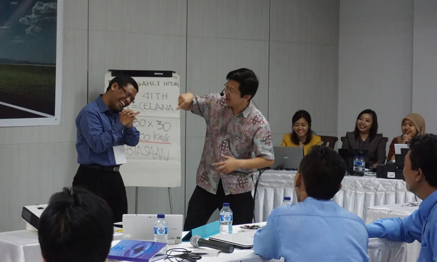 Peserta training tertawa saat Andreas Hartono membahas kebiasaan pengeluaran di depan flipchart